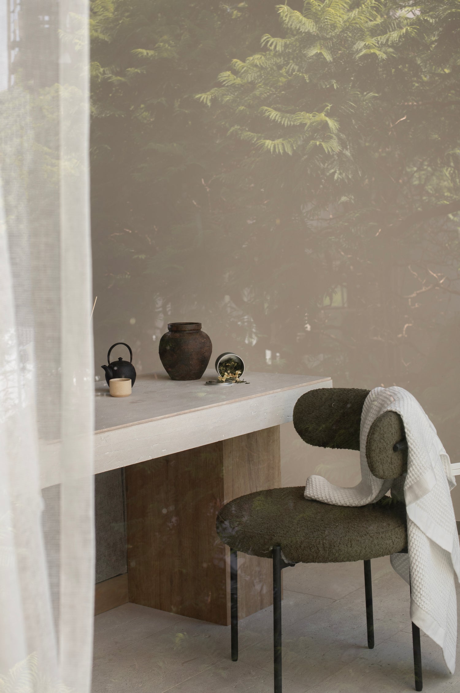 Interior con silla, mesa, té , tetera y taza. Toalla colgada sobre la silla