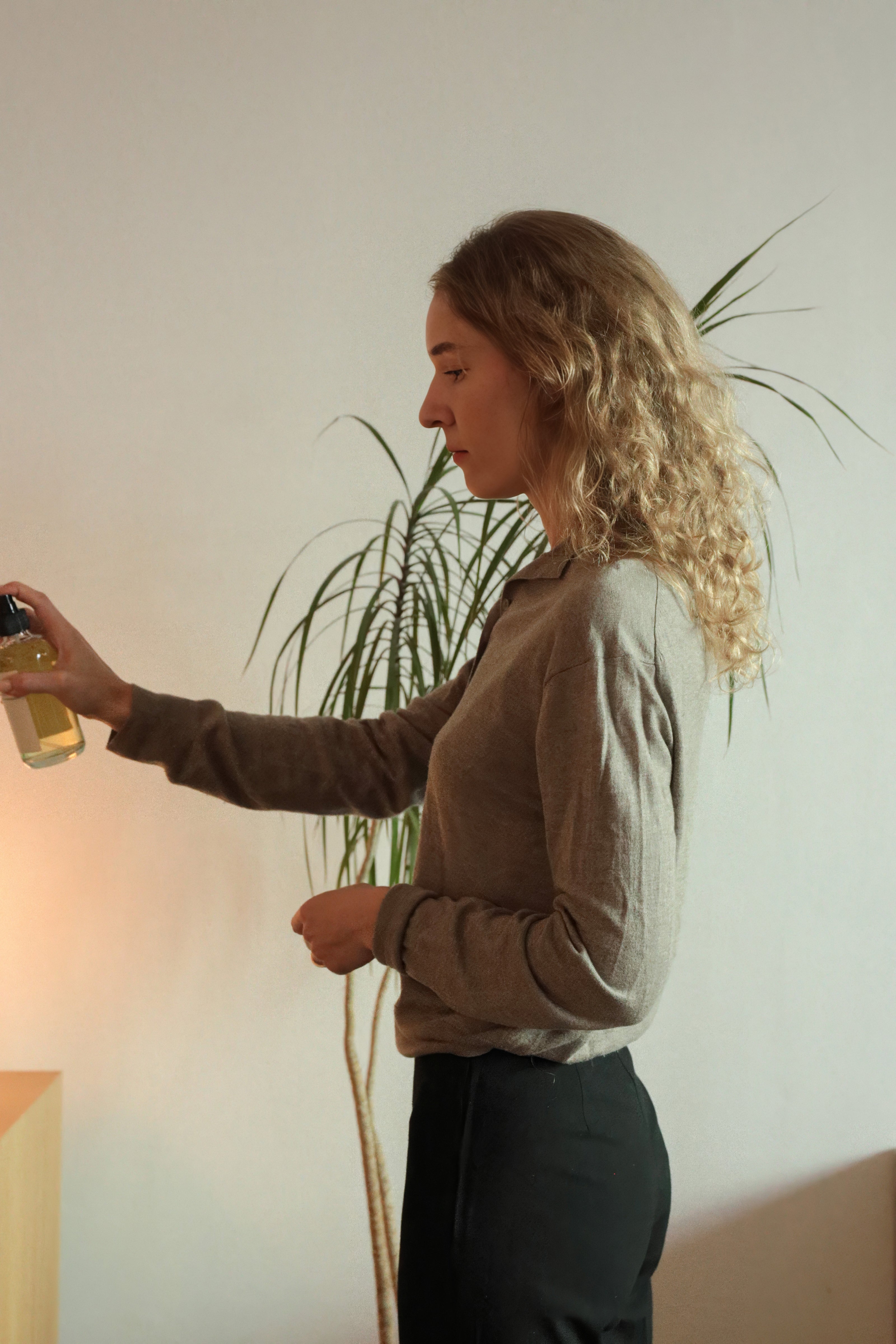Mujer rubia rociando perfume para ambiente Laguna Cyprien Mossa Borea en una sala