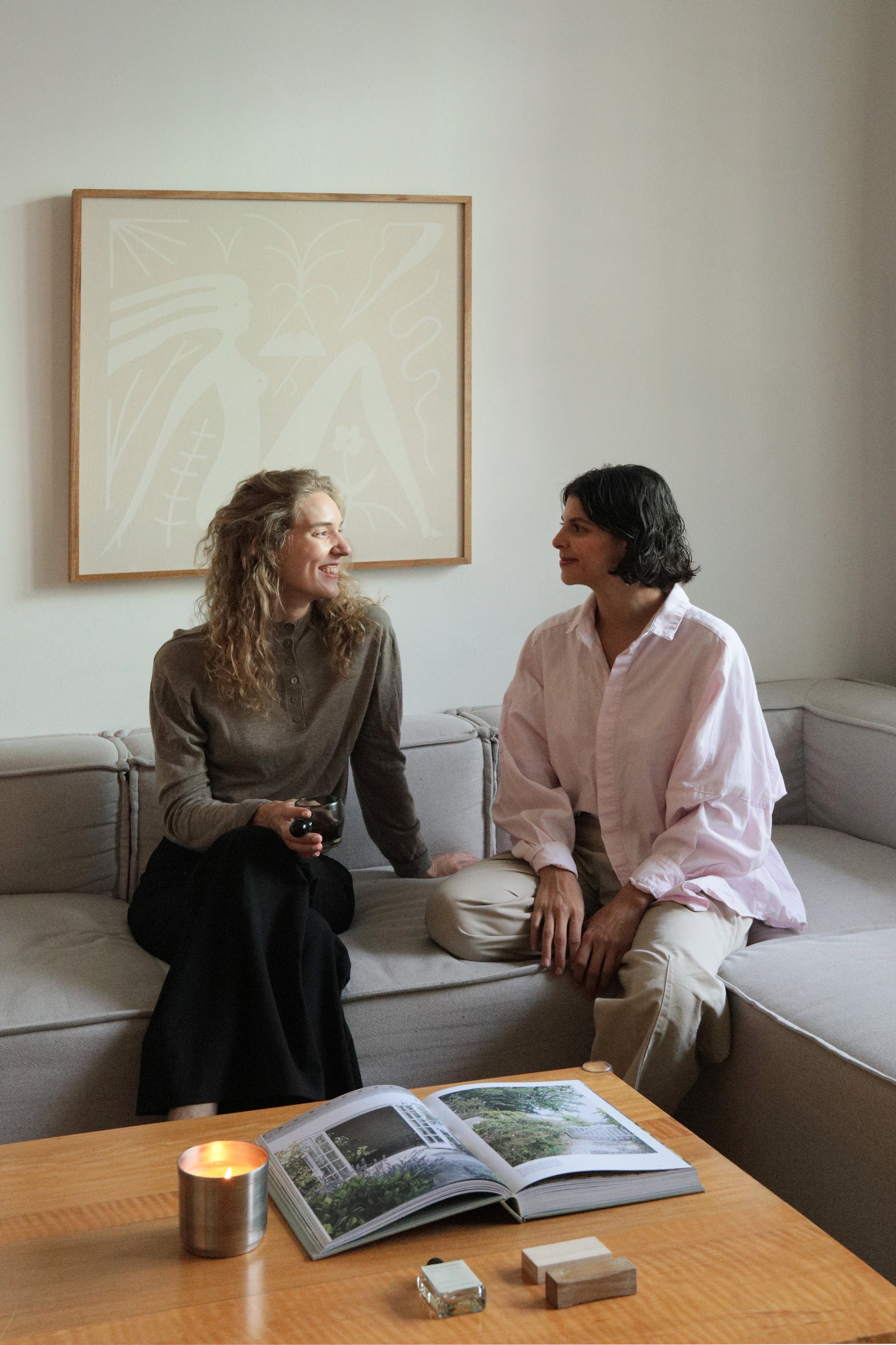 Foto de Maria y Katarina, las fundadoras de Laguna Cyprien en una sala con una vela aromática Laguna Cyprien prendida y unos inciensos de Laguna Cyprien