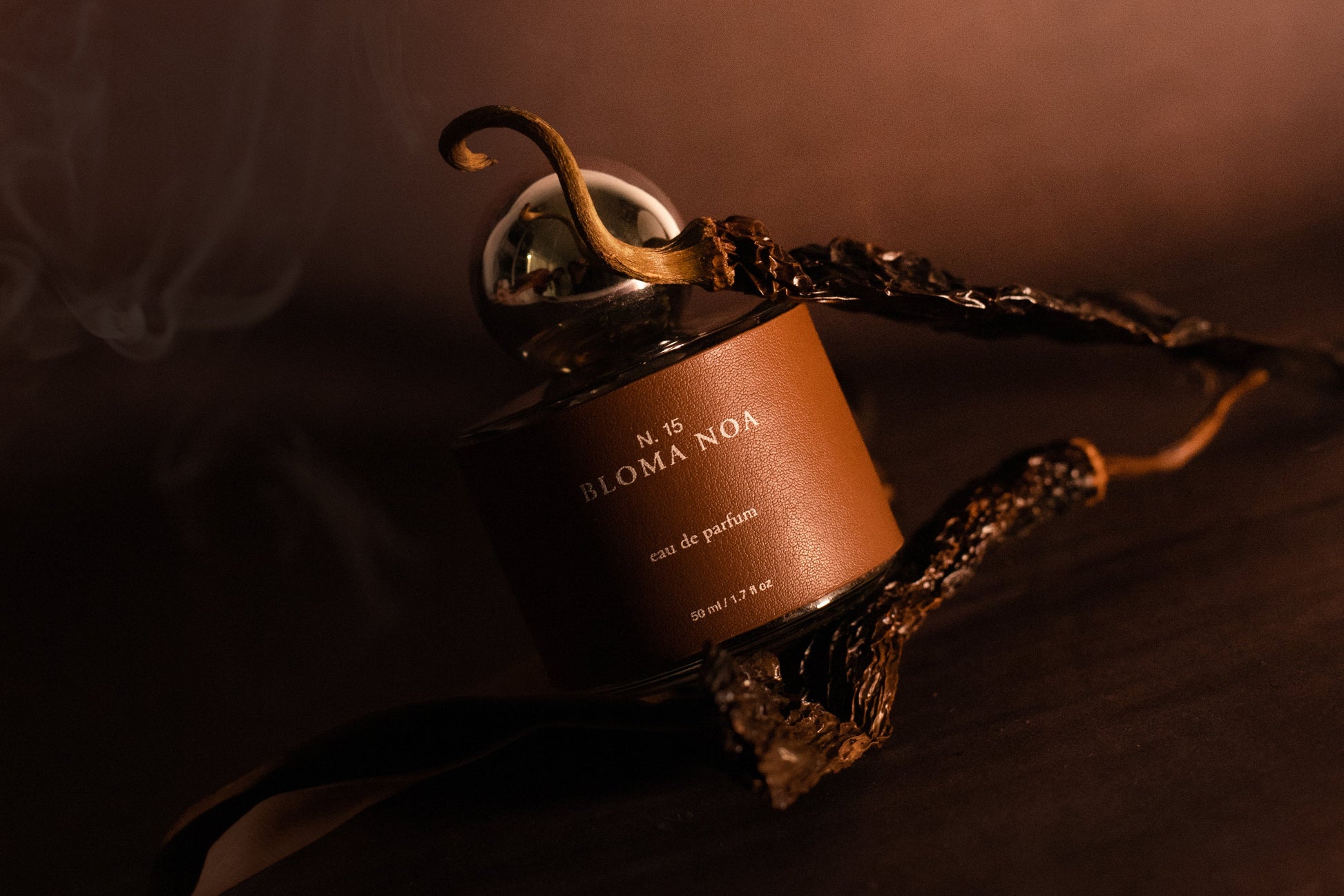 Perfume Bloma Noa de Laguna Cyprien con estética cálida y ahumada, botella de fragancia artesanal sobre superficie en tonos terracota con humo envolvente, inspirado en la fuerza femenina y raíces mexicanas